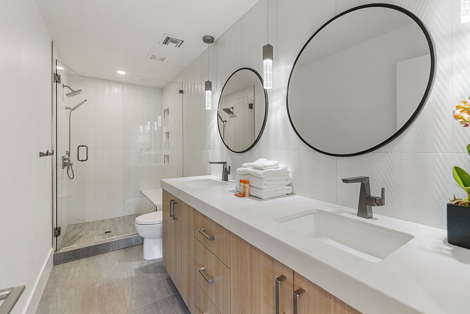 A modern bathroom with a glass shower enclosure, a white sink, and a large mirror.