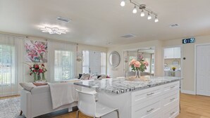 Une cuisine moderne avec un îlot en marbre, des meubles blancs et un grand miroir.