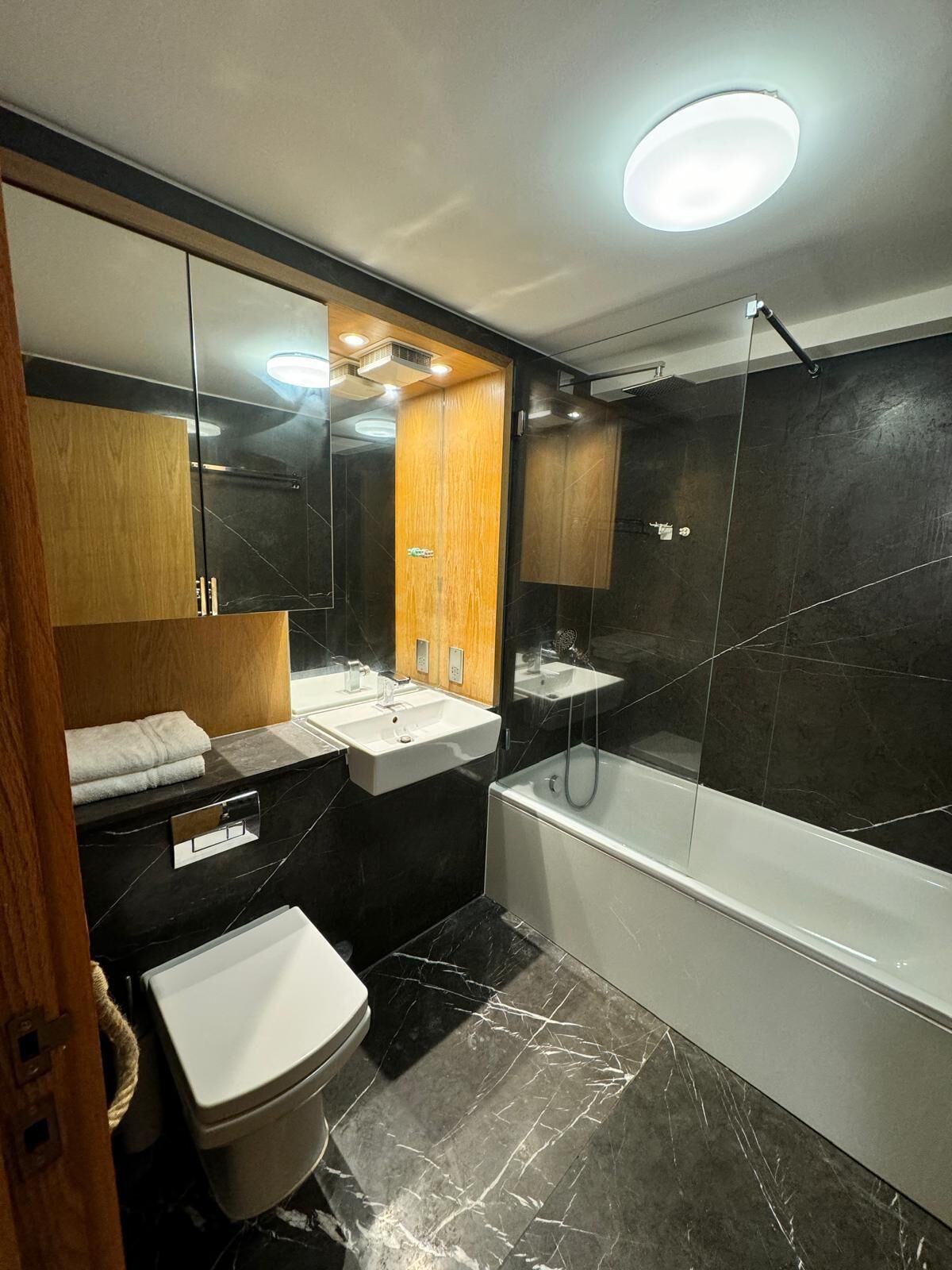 A modern bathroom with a vanity, sink, toilet, and bathtub.