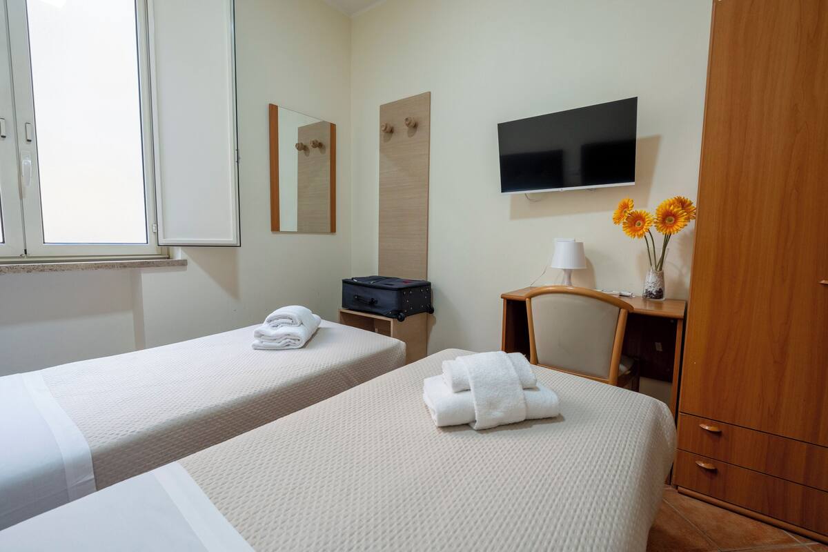 Ett hotellrum med två sängar, en TV, en spegel, ett skrivbord och en garderob.