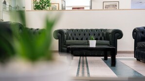 Uma sala de estar moderna com um sofá verde escuro, uma mesa de centro com uma planta e uma mesa de centro de vidro em primeiro plano.