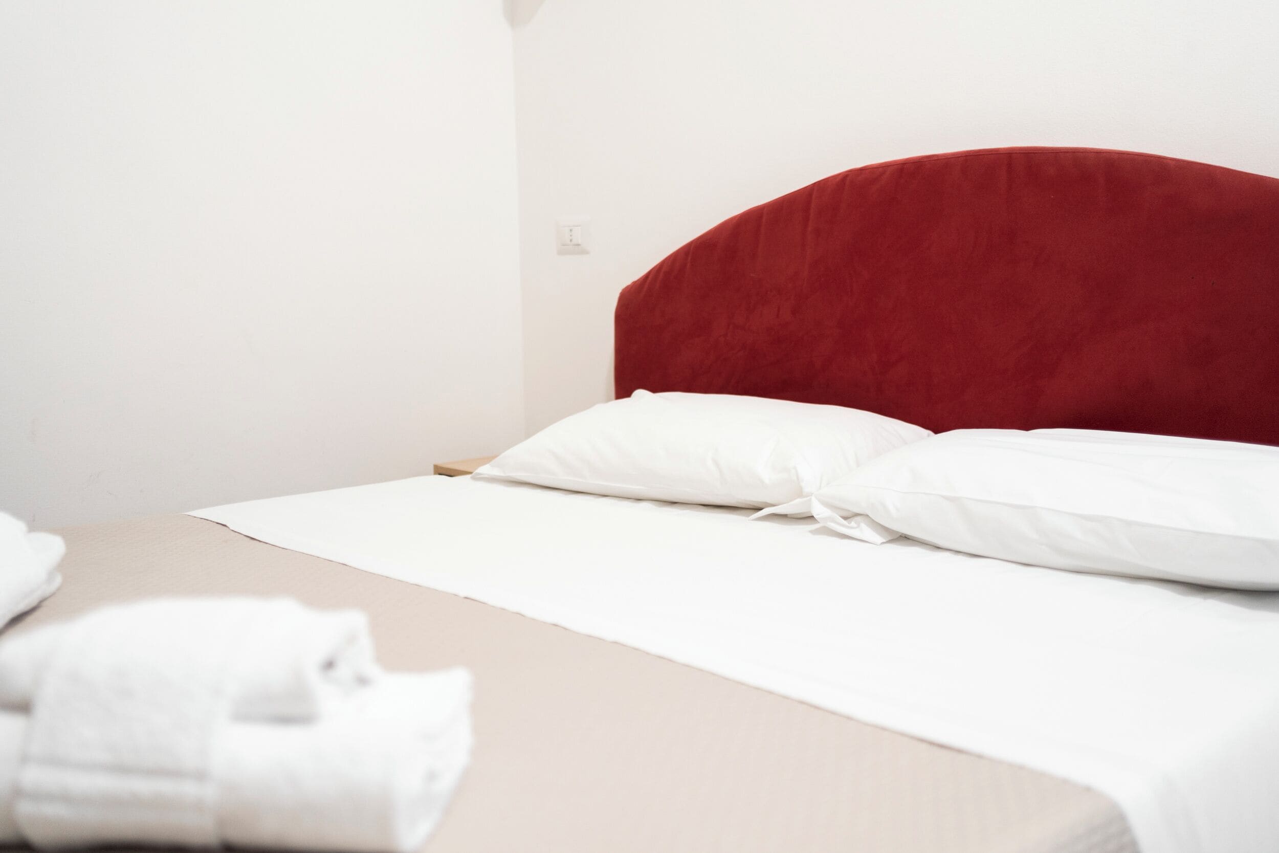 A bed with a red headboard, white pillows, and a beige bedspread.