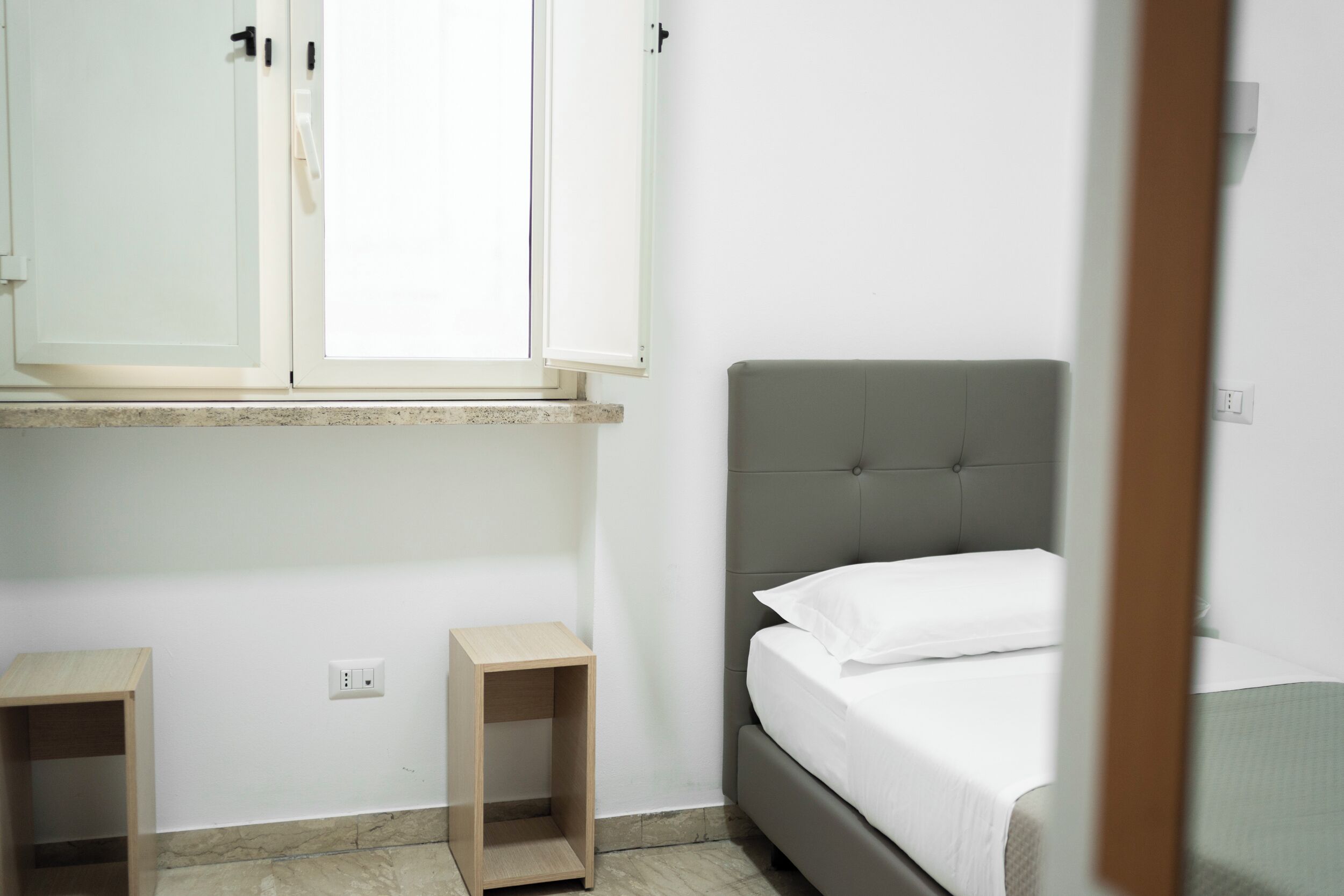 Un dormitorio con cama, mesita de noche, armario y ventana.