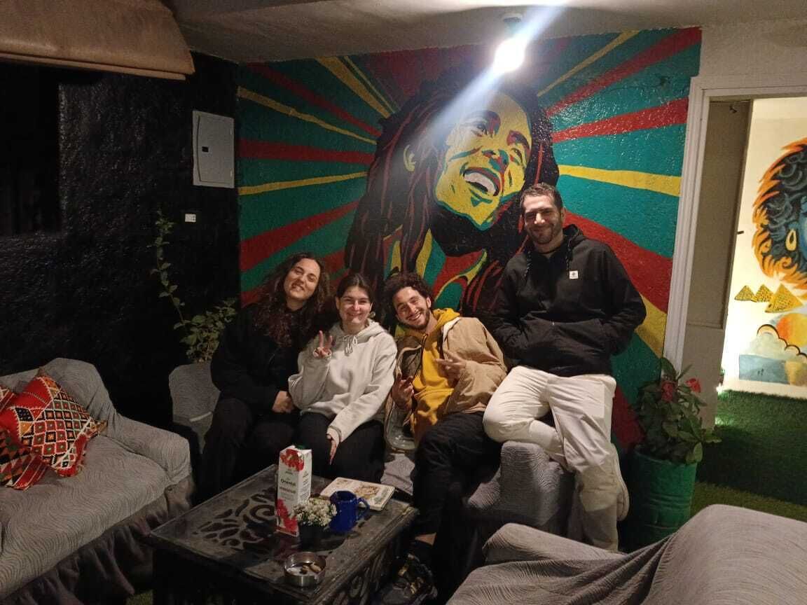 A group of people sitting on a couch in a room with a colorful mural on the wall.