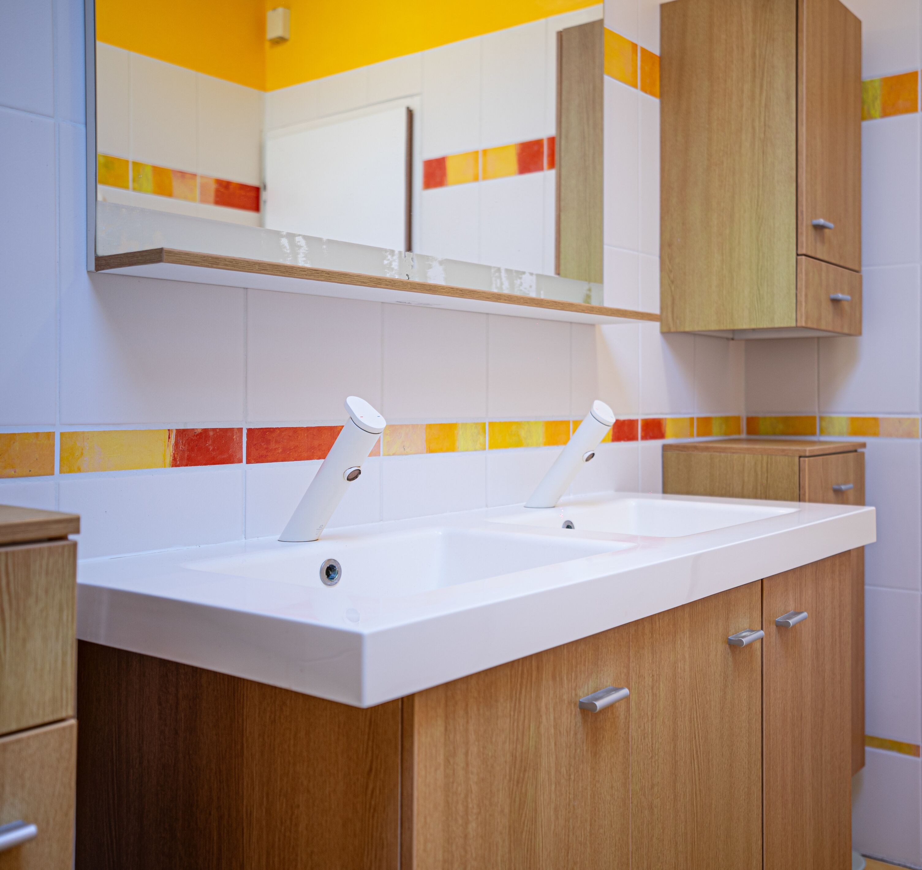 A bathroom with a white sink, wooden cabinets, and a mirror above the sink.