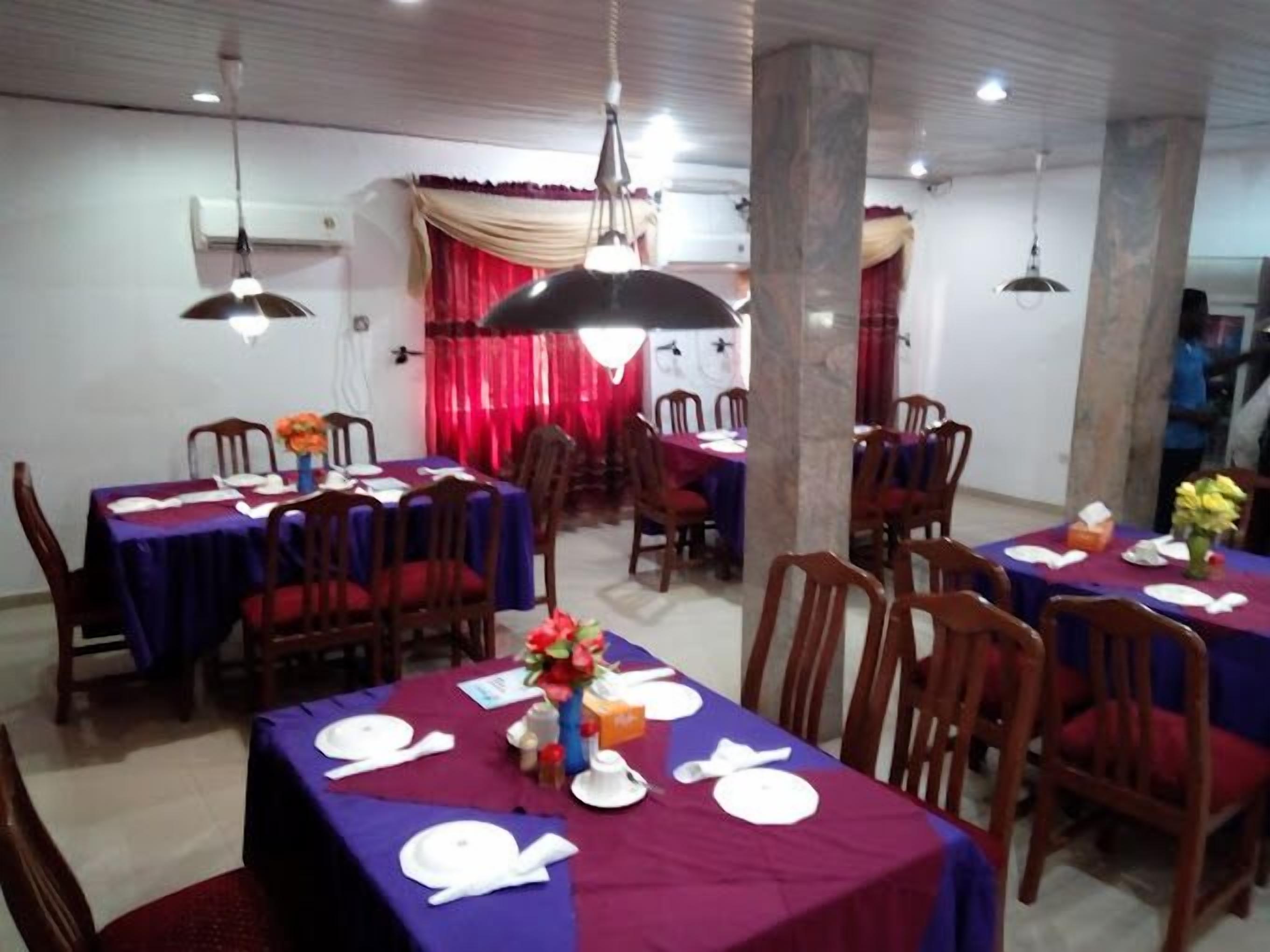 A dining area with tables set for four, each with a purple tablecloth and white plates.