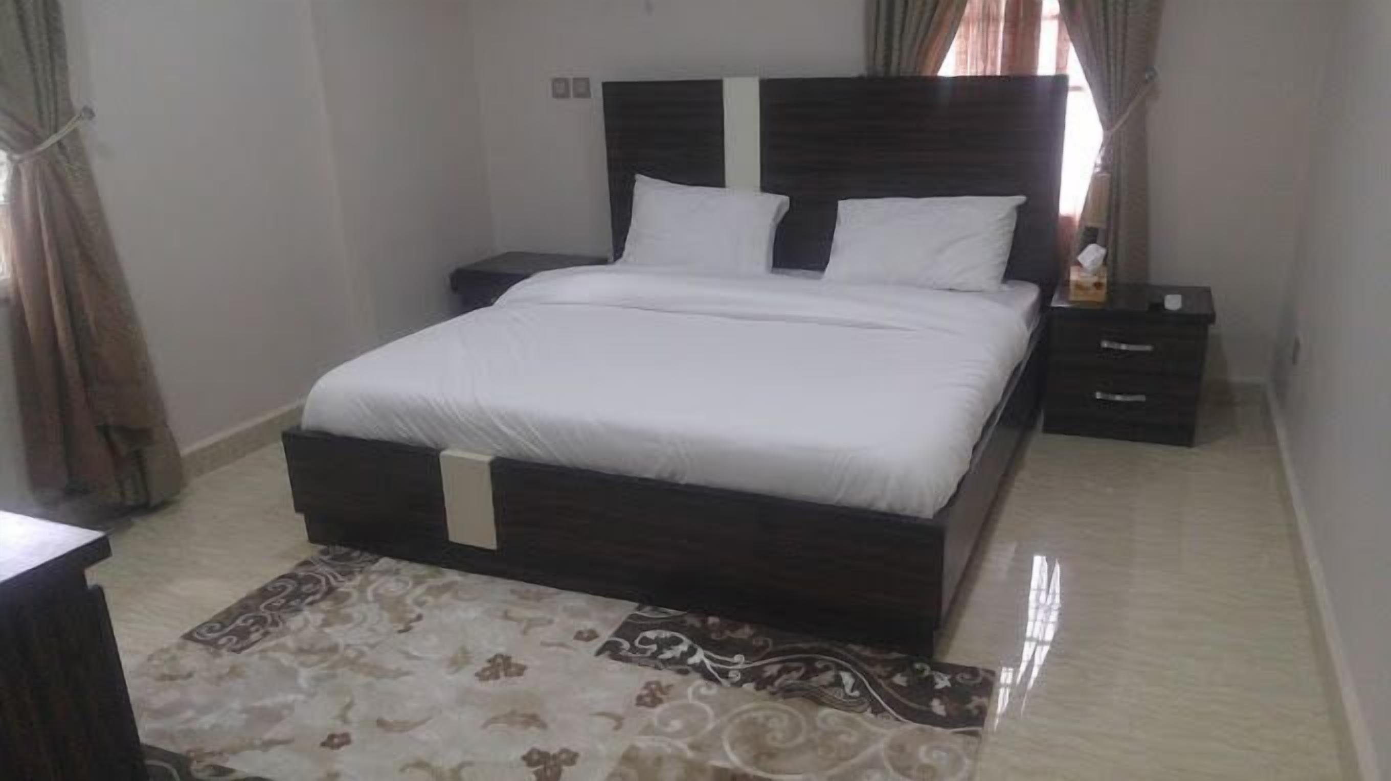 Een net opgemaakt bed met witte beddengoed in een kamer met een donker houten hoofdbord.