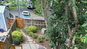 A patio area with outdoor furniture, a wooden deck, and a garden with various plants. - Old Town Gem – Steps to Cafés, Shops & Metro! (Alexandria)