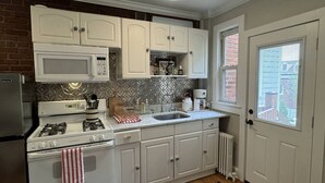 A kitchen with white cabinets, a microwave, a stove, and a sink. - Old Town Gem – Steps to Cafés, Shops & Metro! (Alexandria)