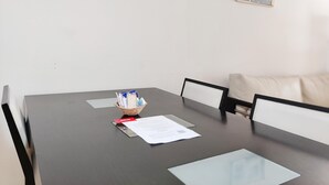 Een vergaderruimte met papieren, een etui met schrijfwaren en een ingelijst beeld aan de muur.