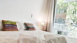Een net opgemaakt bed met bloemenbedrukking, twee kussens en opgerolde handdoeken.