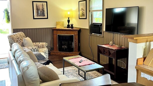 A living room with a sofa, a coffee table, a fireplace, a television, and a wooden cabinet.