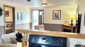A kitchen with a black stove, wooden cabinets, and a countertop. There is a knife block on the counter and a toaster.
