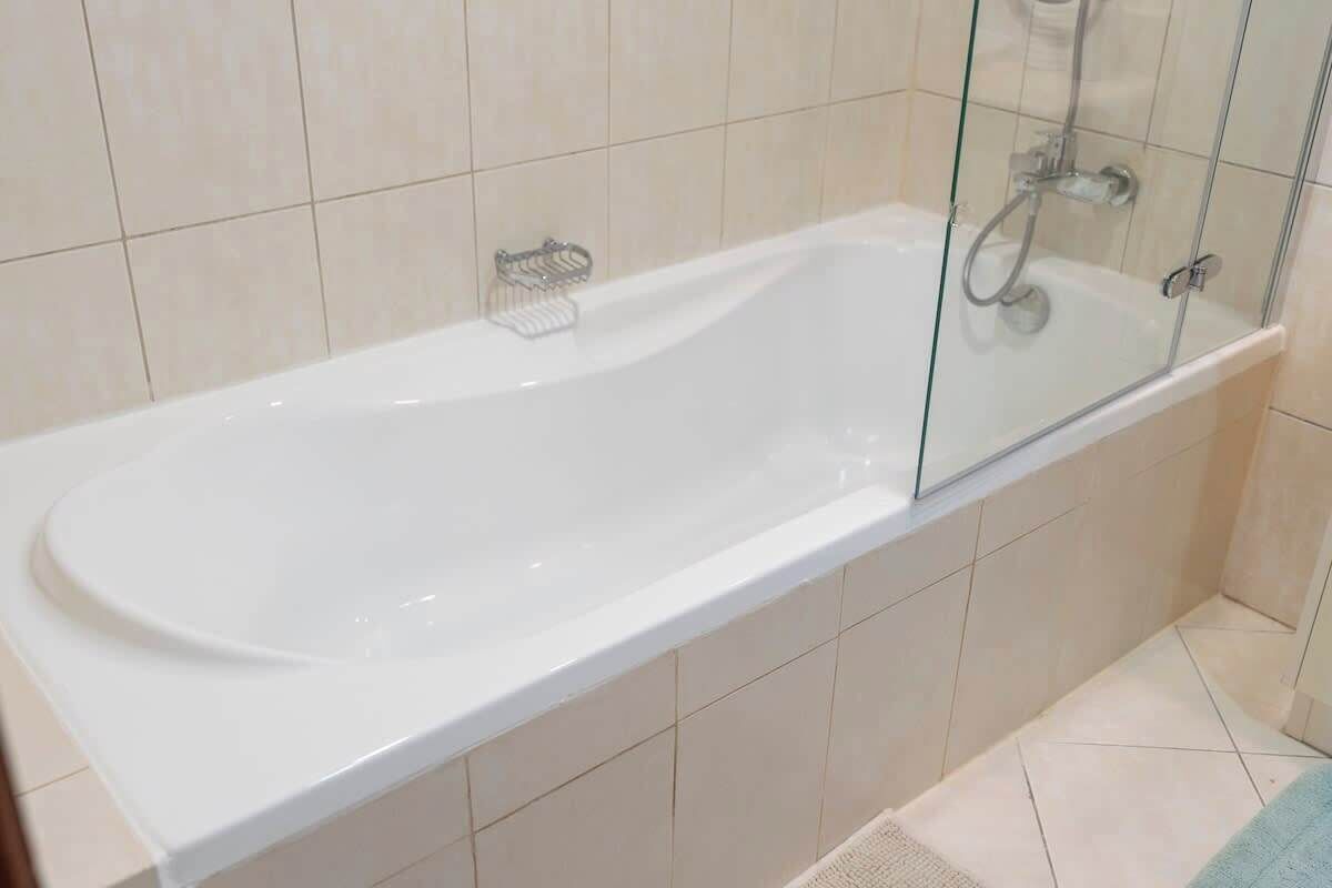 A modern bathroom with a glass-enclosed bathtub, a shower area, and a tiled floor.