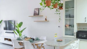 Una cocina moderna con armarios blancos, un microondas y un comedor con una mesa redonda y sillas blancas.