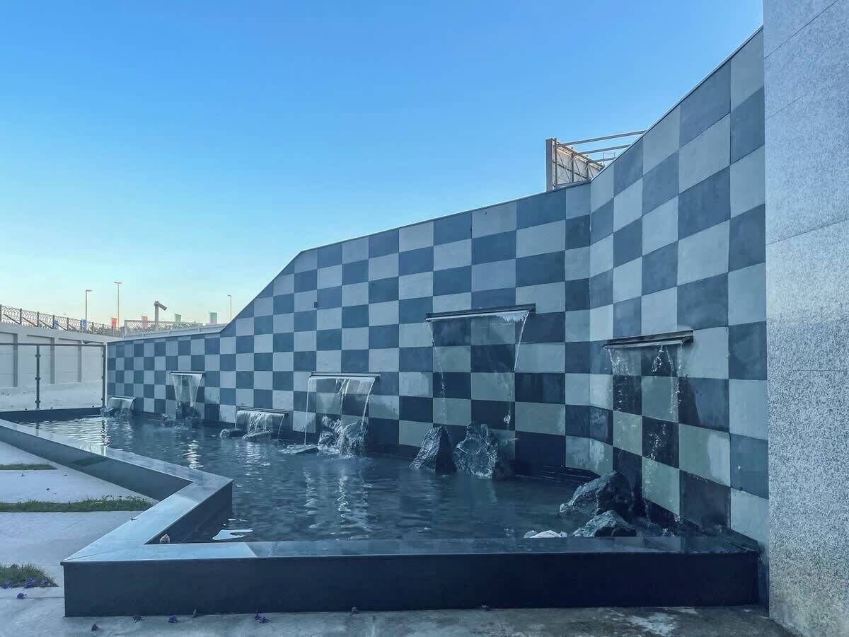 A modern outdoor water feature with checkered wall tiles and multiple water jets.