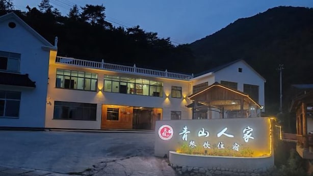 Un hôtel moderne doté d’une entrée bien éclairée, d’une enseigne avec des caractères chinois et d’un chemin de pierre menant à l’entrée.