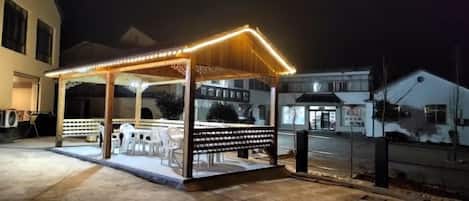 A gazebo-style outdoor seating area with a roof and benches, surrounded by a low wall.