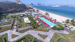 A hotel with a pool area, beach access, and a view of the ocean. - StayShort - Cozy 2BR in Palm Jumeirah with Beach Views! (Palm Jumeirah)