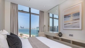 A modern hotel room with a large bed, a view of the sea, and a cityscape. - StayShort - Cozy 2BR in Palm Jumeirah with Beach Views! (Palm Jumeirah)