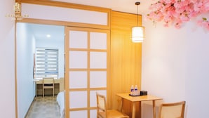 A room with a sliding door, a desk with a chair, a small table with two chairs, and a hanging light fixture. - Lotus Land Apartment (Hanoi)