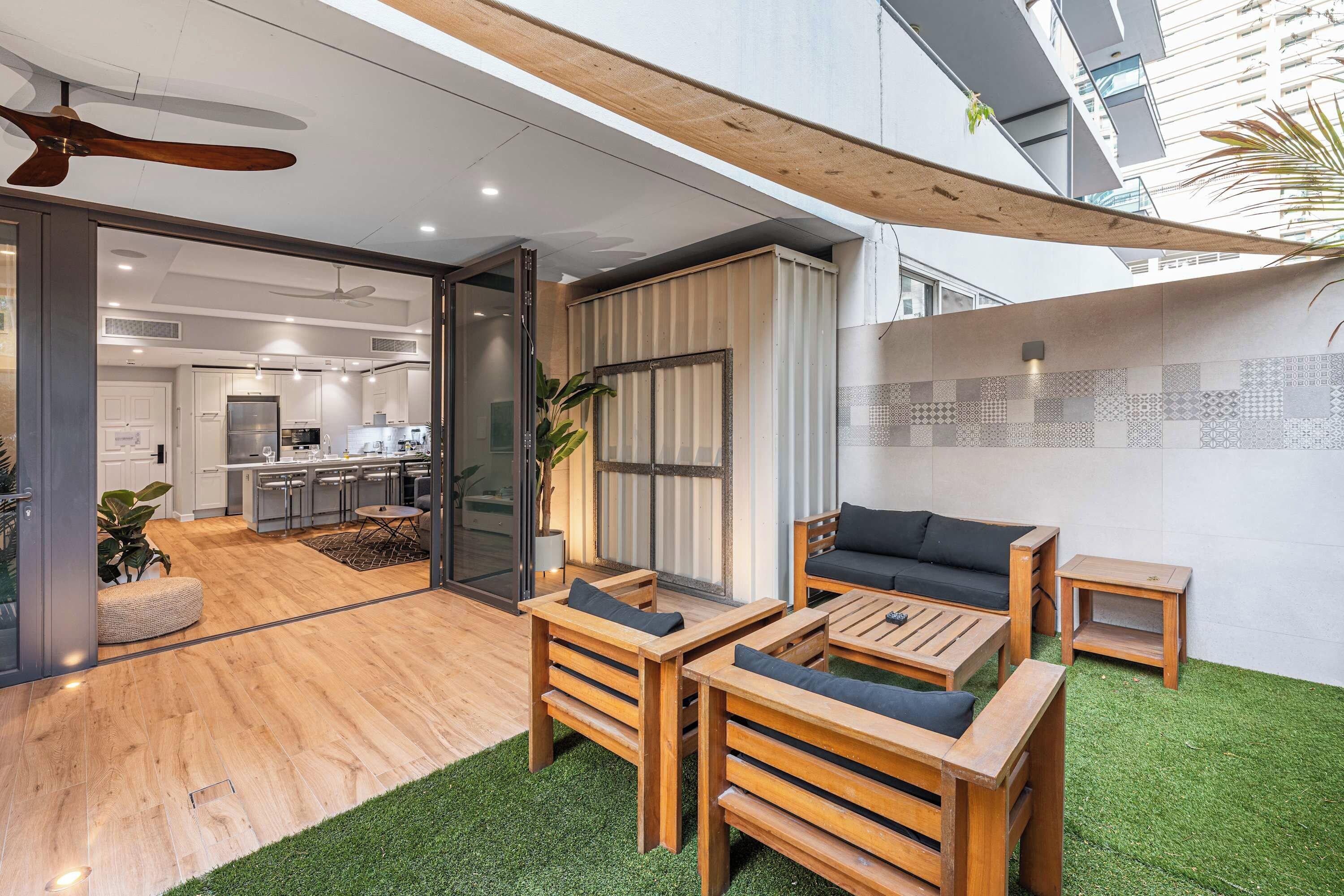 A modern interior with a dining area, kitchen, and a balcony with artificial grass.