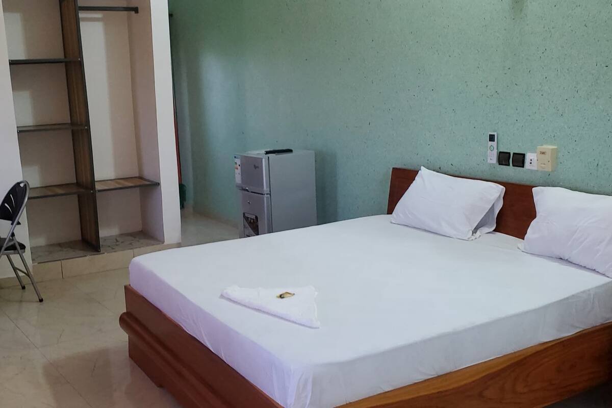 A hotel room with a bed, a desk, a chair, and a wardrobe.