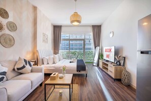 Un salon moderne avec un canapé, une table basse, un meuble pour la télévision et une grande fenêtre avec des rideaux.