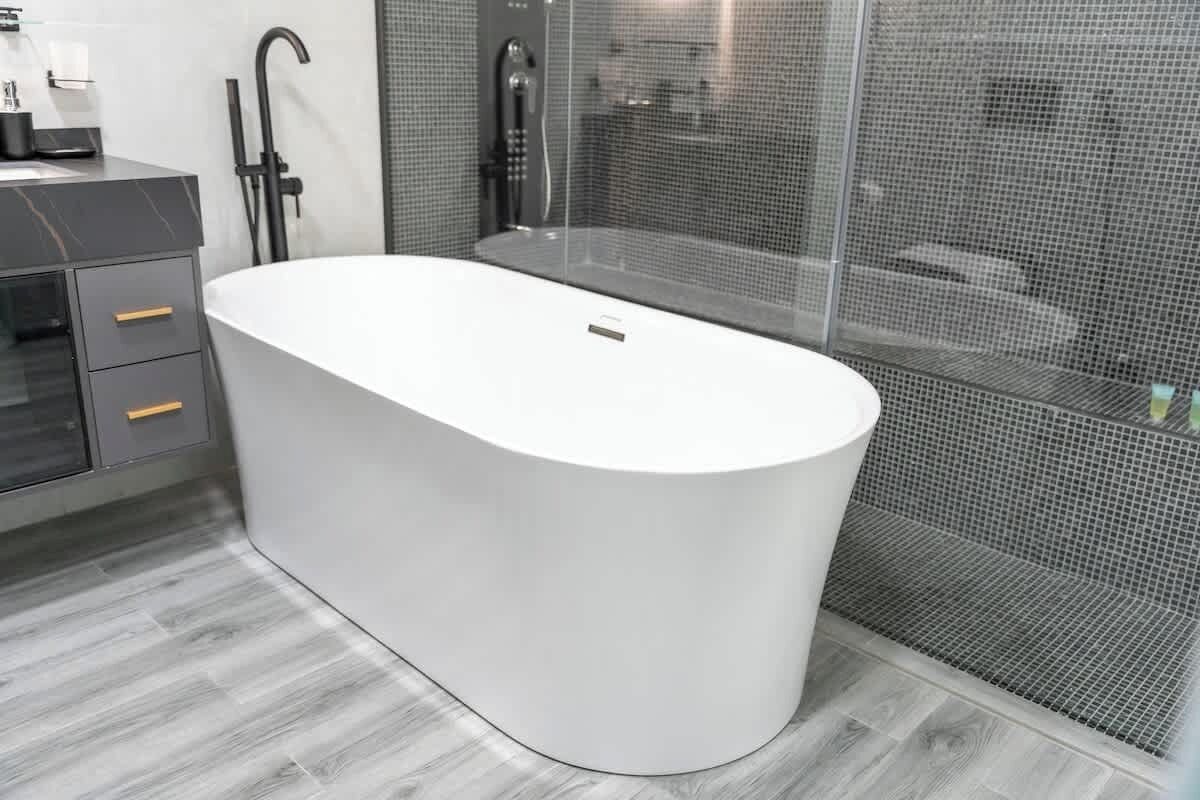 A modern bathroom with a freestanding bathtub, a shower area with a glass enclosure, and a grey tiled wall.
