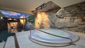 Un bain à remous avec un mur de pierres en arrière-plan et une fresque représentant une cascade.