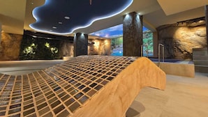 Un espace spa moderne avec un banc en bois, des murs en pierre et une vue sur un paysage naturel.