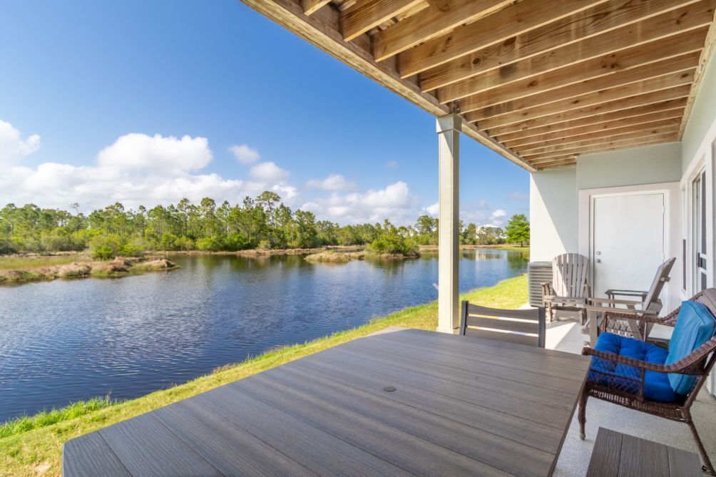 A covered outdoor deck with a view of a calm lake and surrounding greenery.
