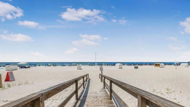 A wooden boardwalk leading to a sandy beach with umbrellas and beach chairs. - Romar Lakes 103B w Pool (Orange Beach)