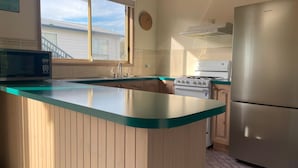 Una cocina con una isla central, microondas, estufa y refrigerador.