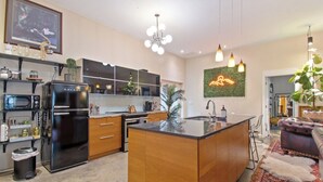 Una cocina moderna con una isla central, electrodomésticos integrados y un letrero de neón decorativo.