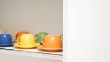 A row of colorful cups and saucers on a shelf.