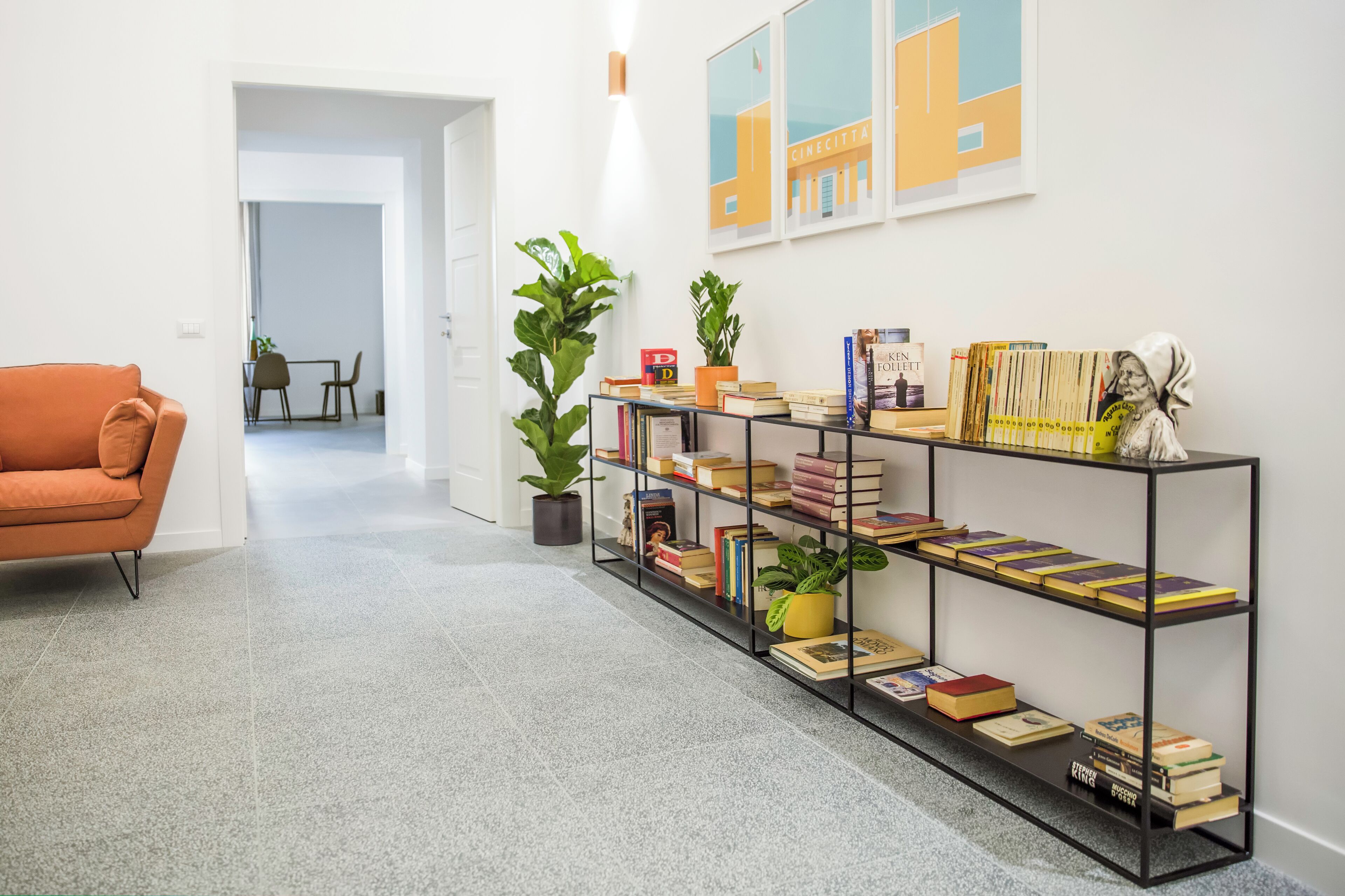 A modern living room with a sofa, a bookshelf filled with books, and a potted plant.