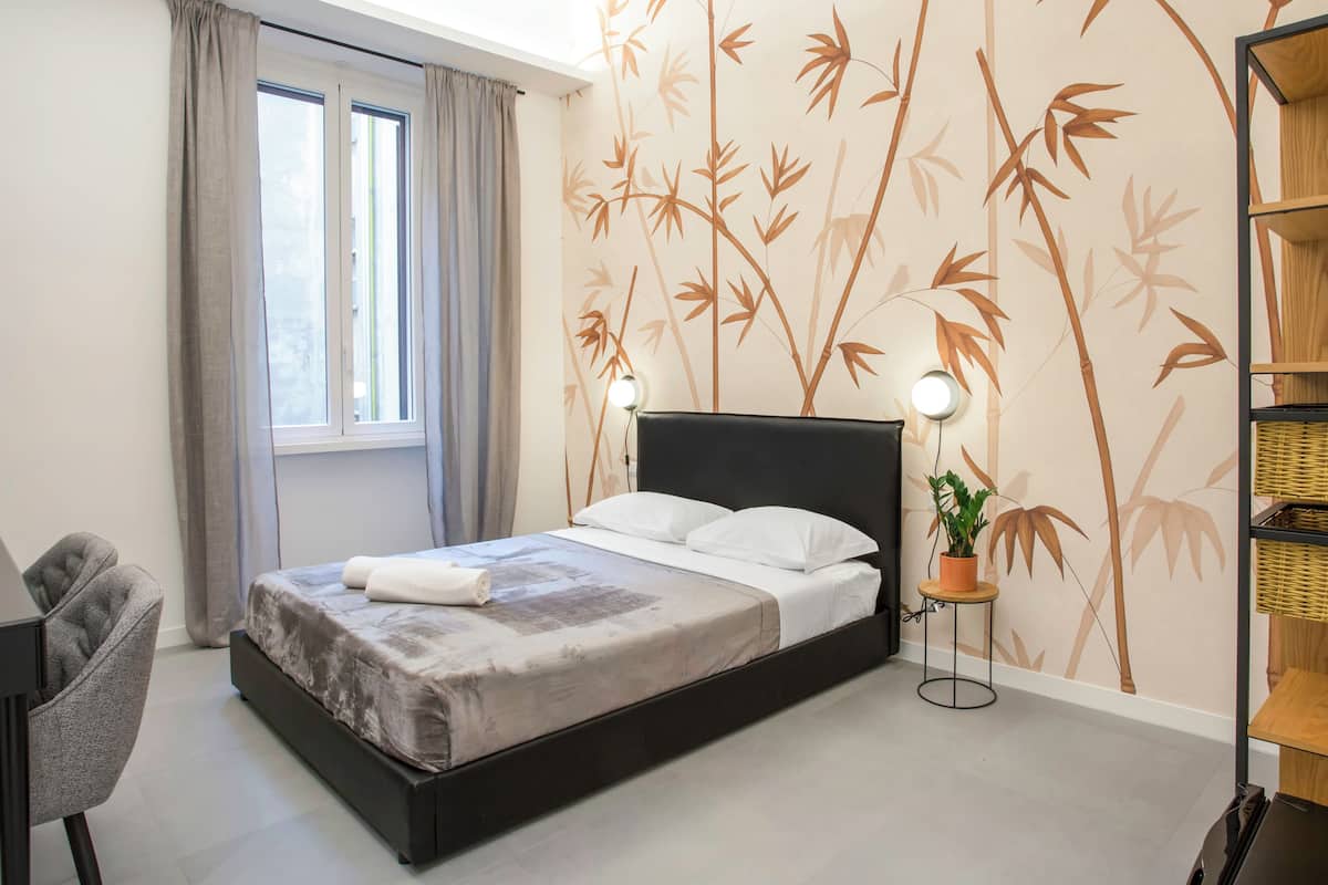 Une chambre à coucher moderne, comprenant un lit, un bureau, une chaise, une lampe et une bibliothèque.