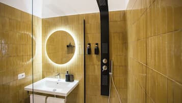 Une salle de bain moderne avec un lavabo blanc, un grand miroir et un panneau de douche noir.