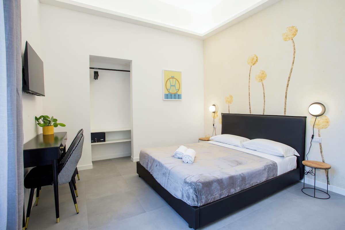 Une chambre à coucher moderne avec un lit, des tables de chevet, un bureau et une chaise.