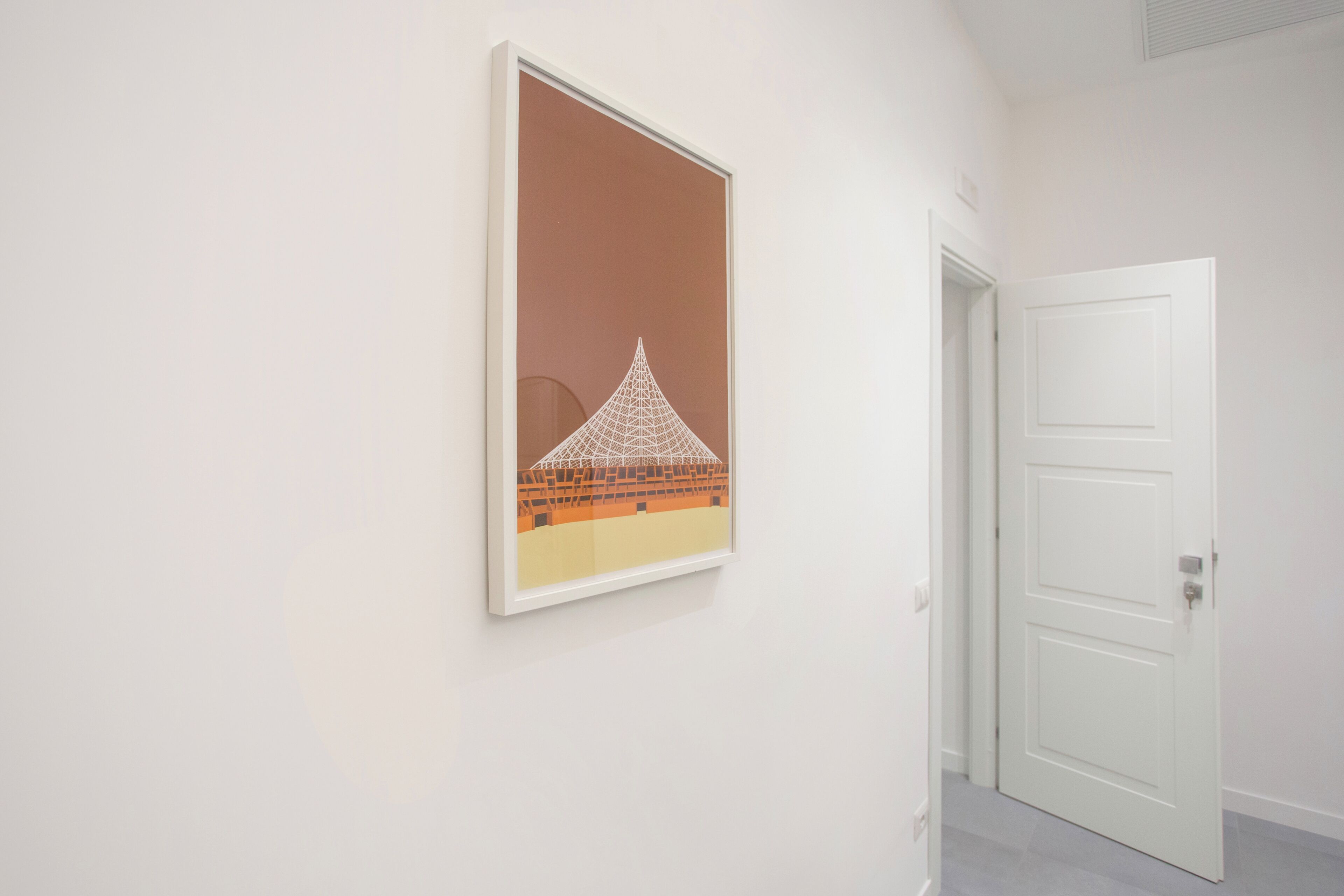 A hallway with a framed artwork on the wall and a closed door.