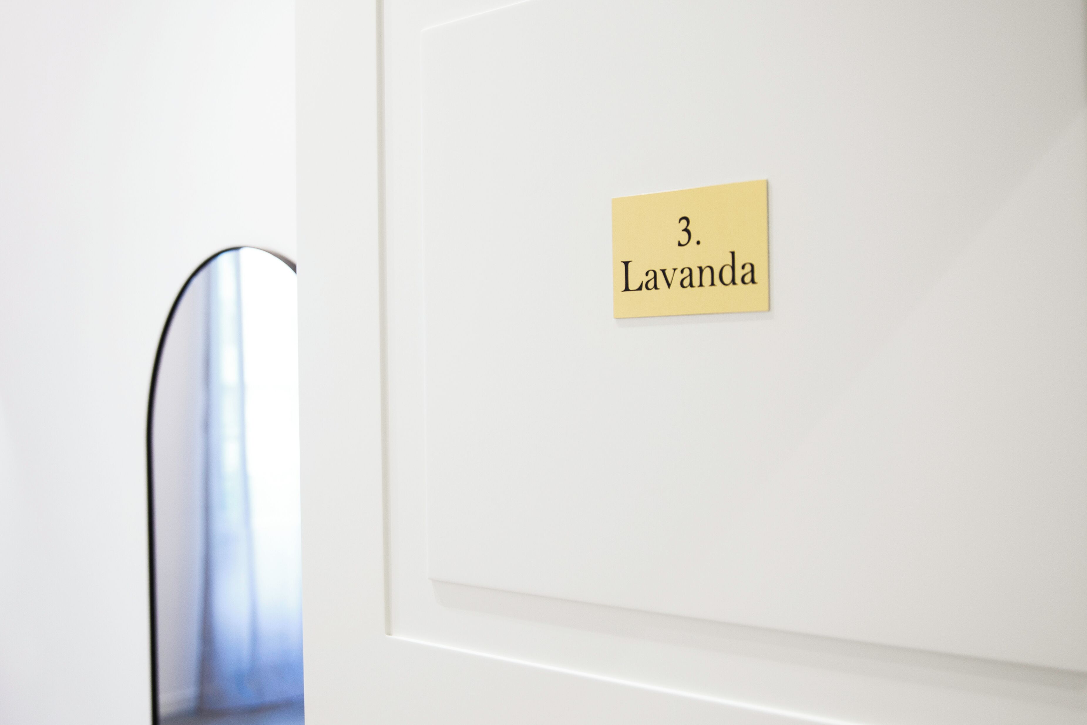 Una puerta blanca con un letrero amarillo que dice "3. Lavanda".