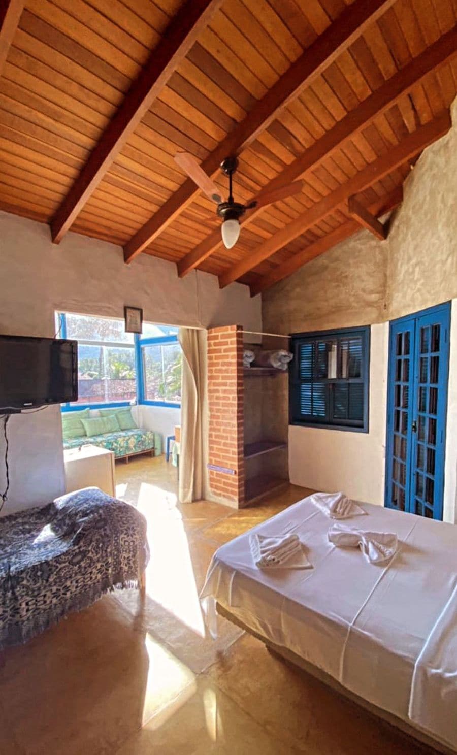 A room with a bed, a fireplace, a television, and a view of the outdoors.