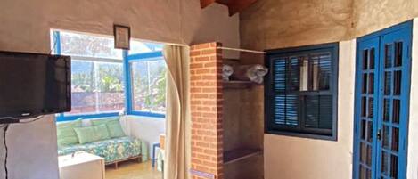 A room with a bed, a fireplace, a television, and a view of the outdoors.