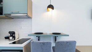 Une cuisine compacte équipée d’une cuisinière intégrée, d’une machine à café et de deux chaises grises.
