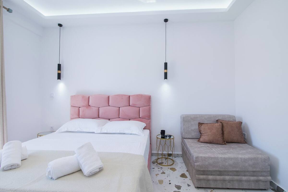 A modern bedroom with a bed, bedside table, and a sofa.