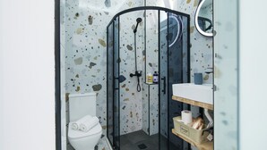 Une salle de bain moderne avec une douche à parois de verre, des toilettes et un meuble-lavabo avec un miroir.