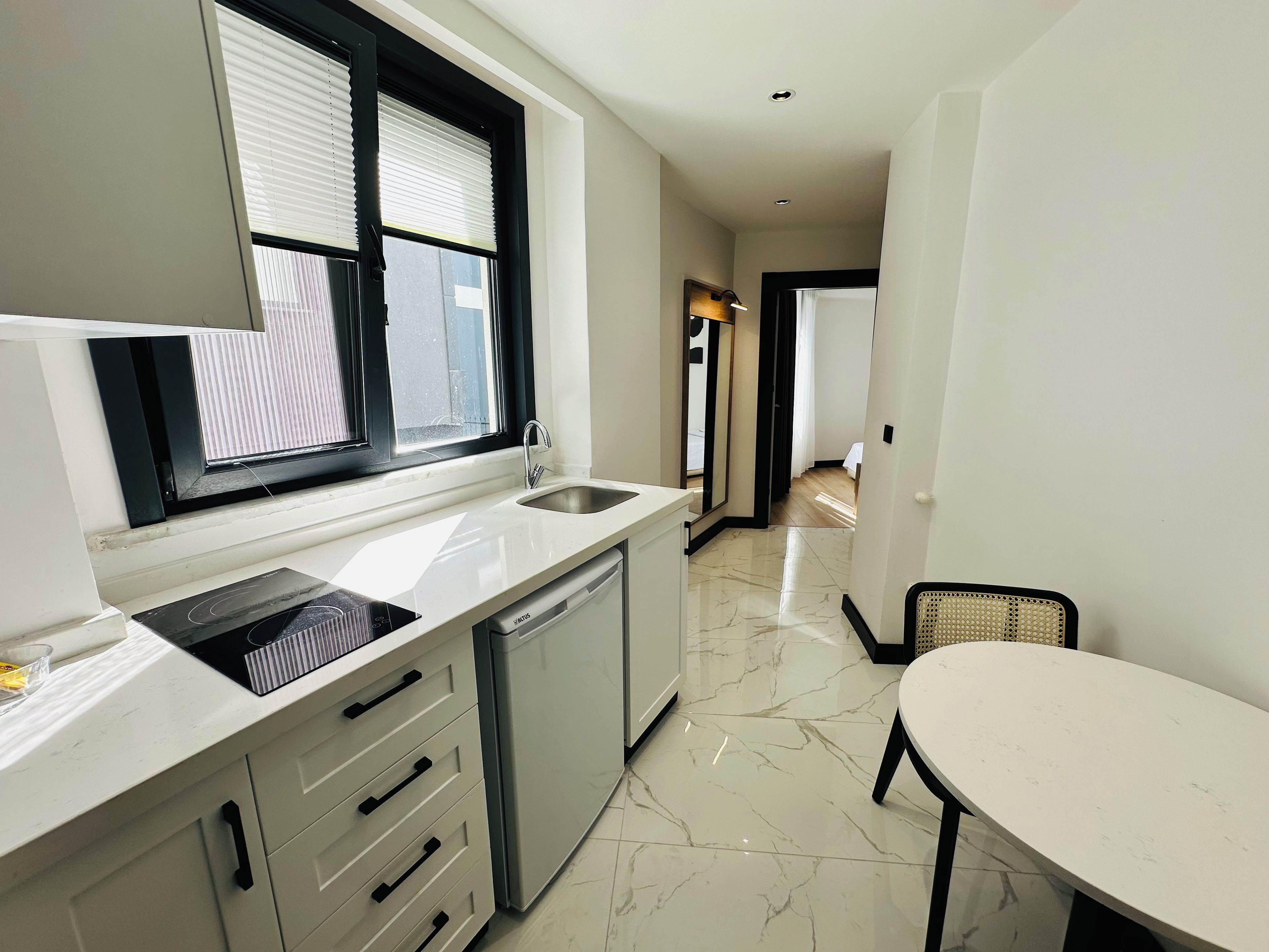 A modern kitchen with a built-in dishwasher, a sink, and a window with blinds.