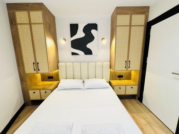 Ein modernes Hotelzimmer mit einem großen Bett, einem Holzkopfschild und einem an der Wand befestigten abstrakten Kunstwerk.