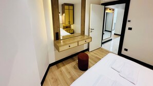 A modern hotel room with a large mirror, wooden wardrobe, and a bedside table. - Rose Point Residence (Istanbul)